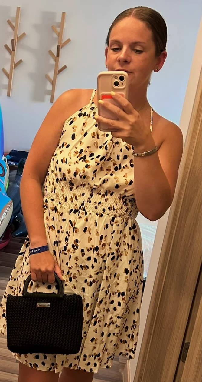 Ali in a patterned summer dress, holding a black crochet tote she made
