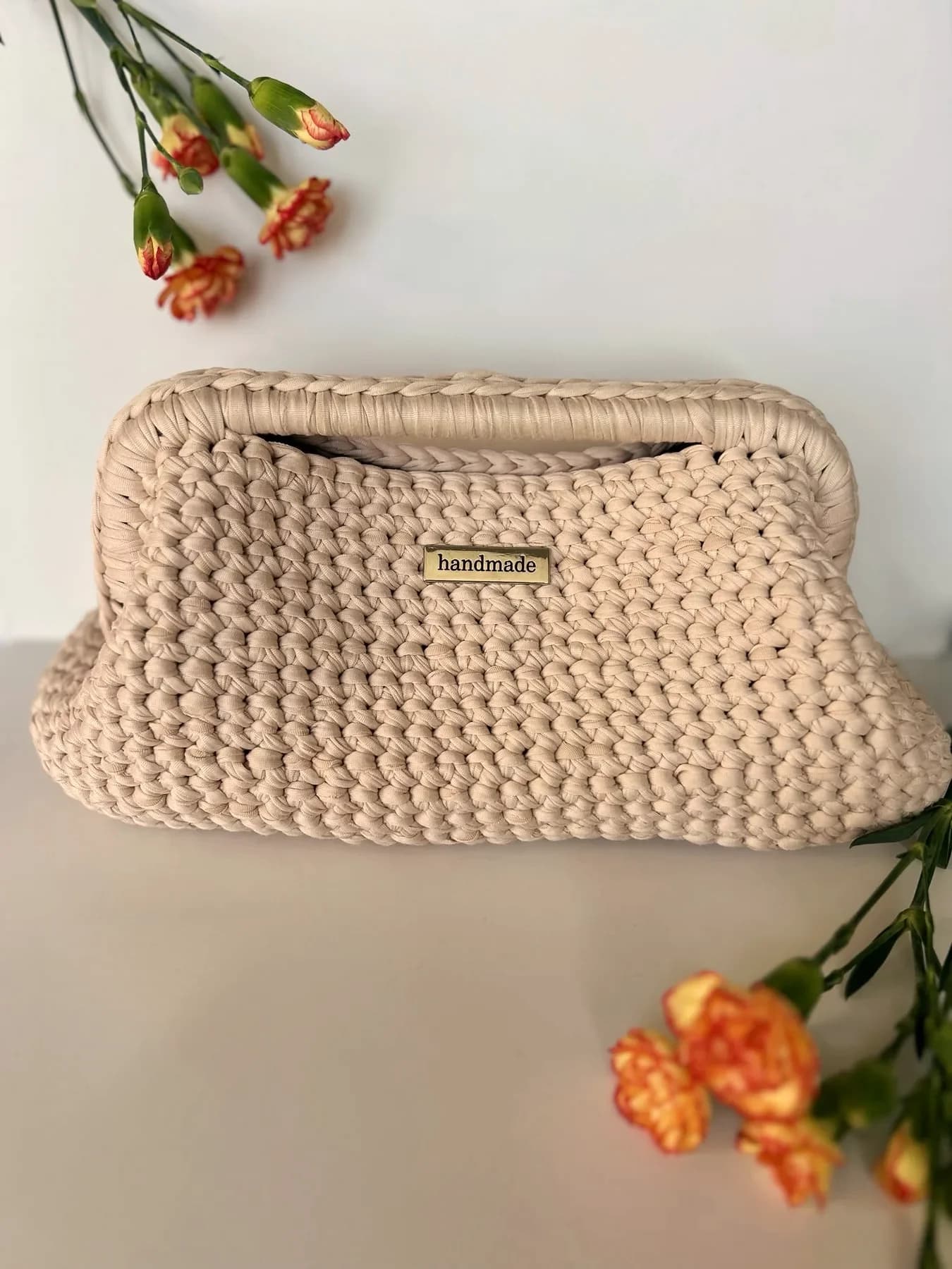 Cream framed crochet clutch made by Ali, with orange carnations